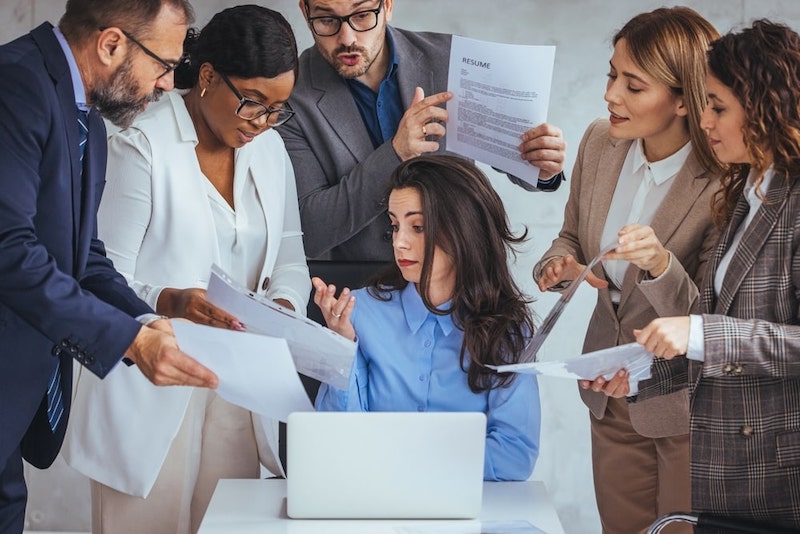 Multiple People Bothering One Woman With Documents In The Office