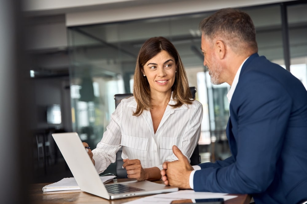 Man In A Suit Talking With His Colleague Sitting At A Table