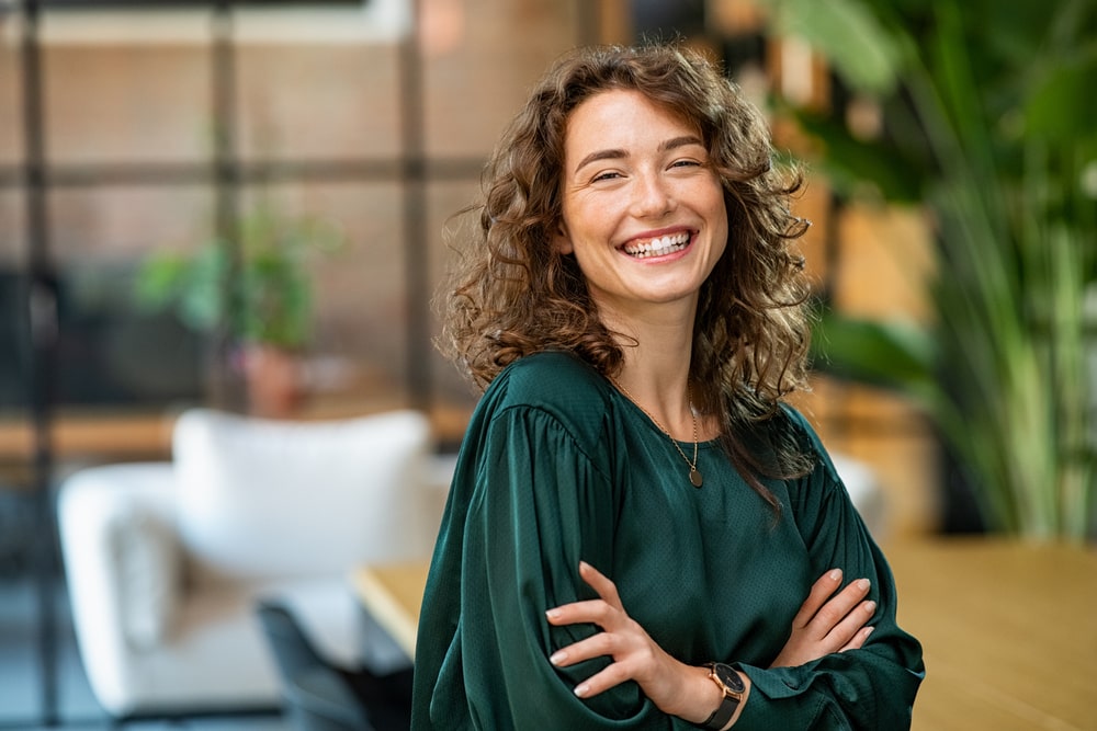 Woman In A Green Shirt Looking At The Camera And Smiling