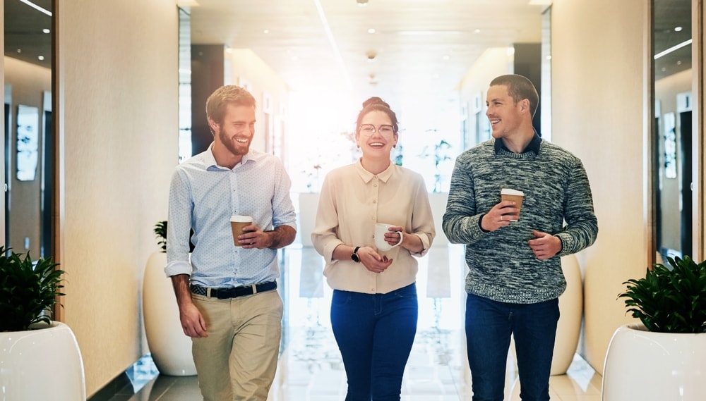 Three teammates walking in an office hallway while having a conversation during a break