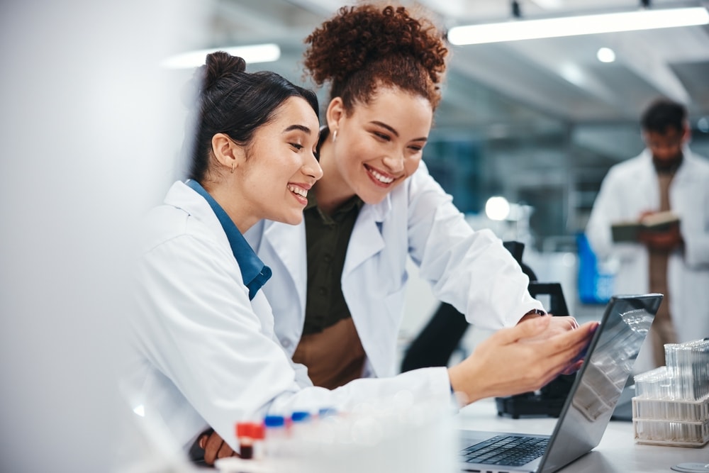 Two hospital staff members having a conversation while looking at a laptop