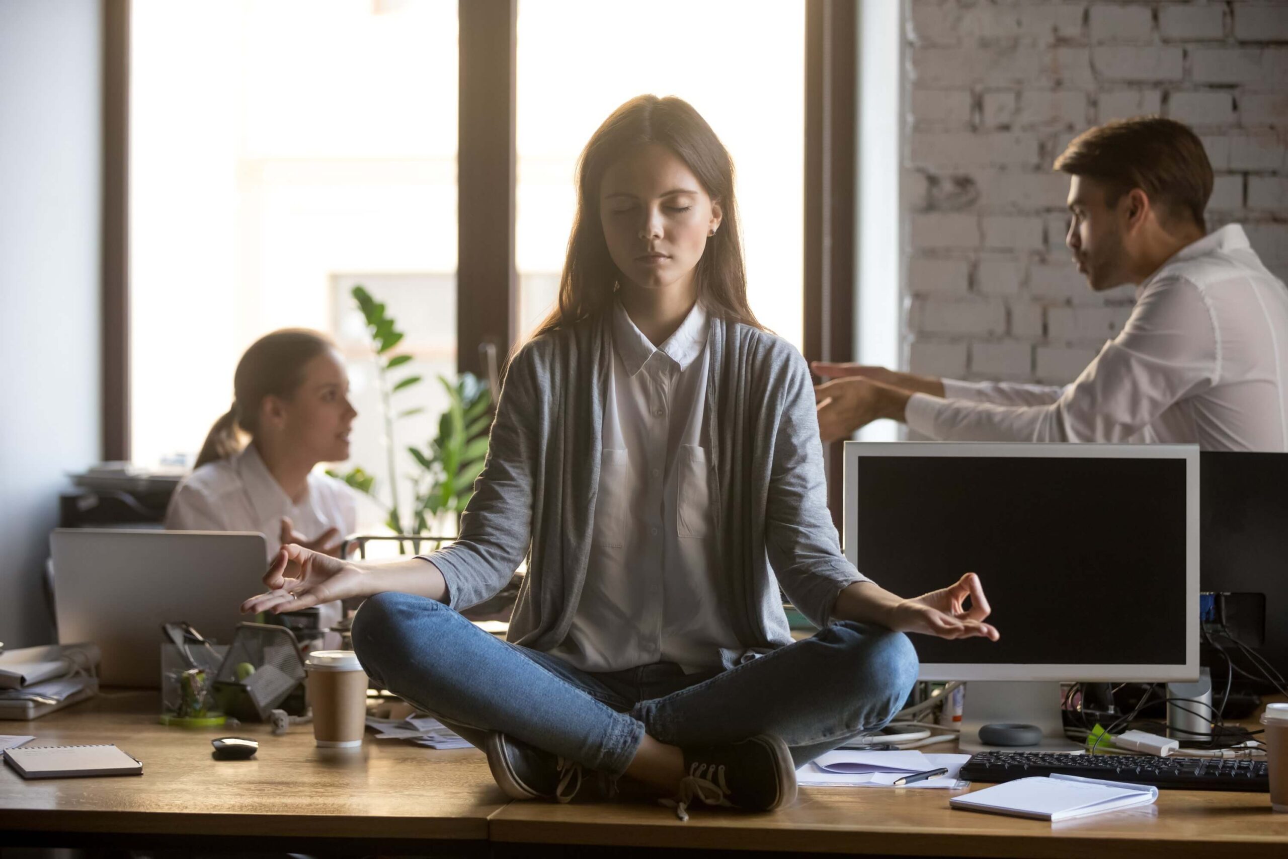 Businesswoman meditating at workplace, avoiding problems at work