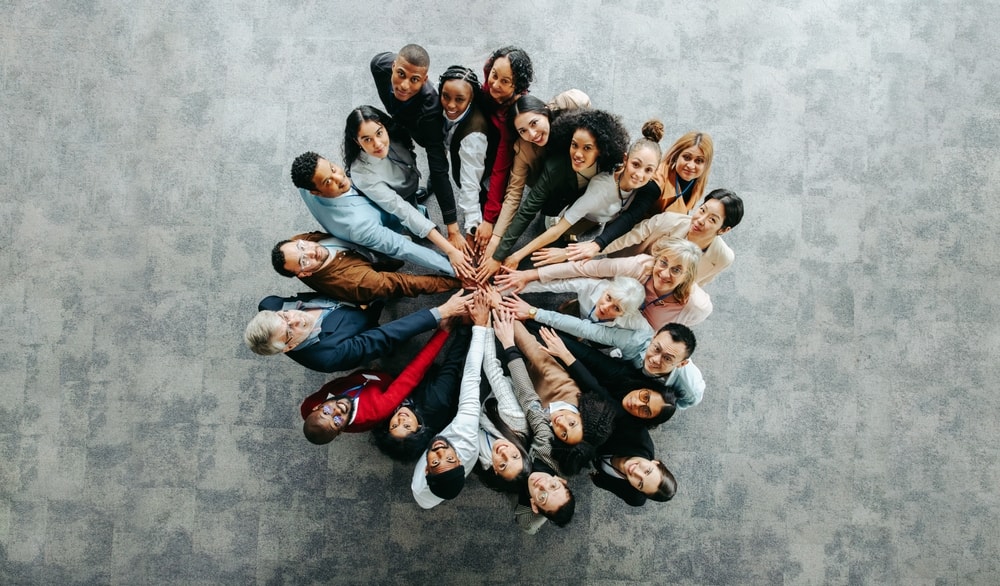 Top view of a diverse team of people joining hands in a collaborative and inclusive business environment, symbolizing unity and teamwork.